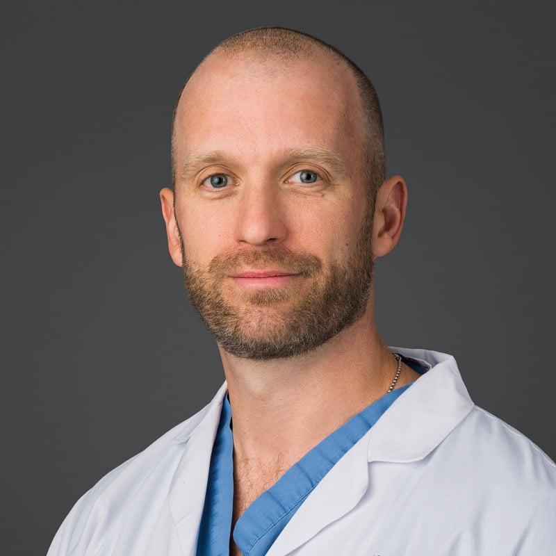Clean and confident studio headshot of a Bronx medical doctor against light gray.