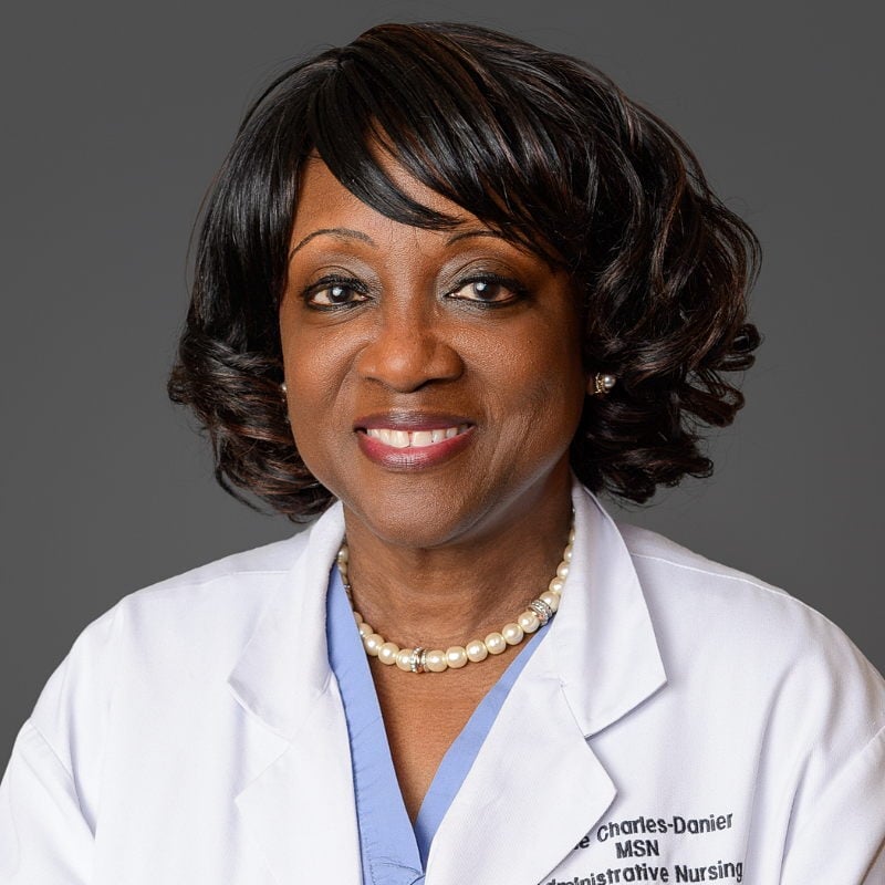 Elegant studio portrait of a female medical doctor in the Bronx, with a dark gray background.