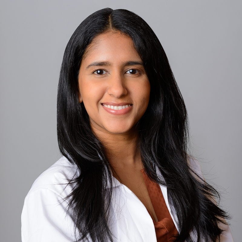 Bright and welcoming headshot of a Brooklyn pediatrician with a white background.