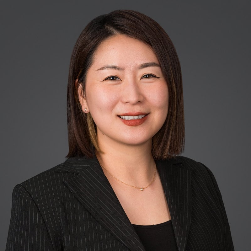 Brooklyn Studio headshot of a confident female surgeon using soft light and a dark gray background.